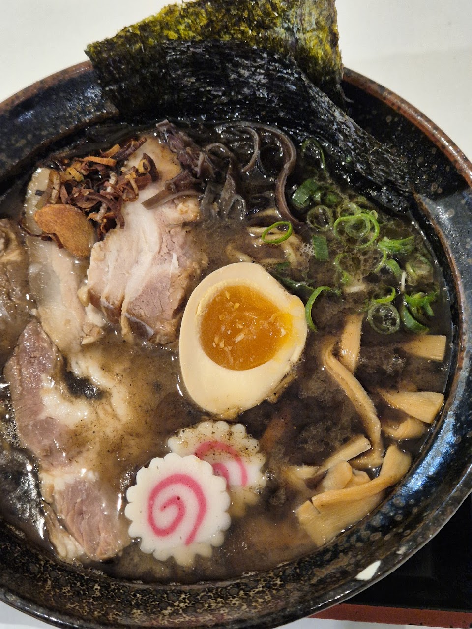 Black bowl ramen with egg, pork, nori, bamboo shoots, and spring onion at Menya Chinatown